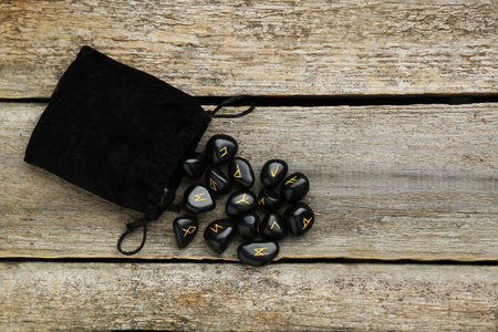 Bag with black rune stones on wooden table, flat layの写真素材