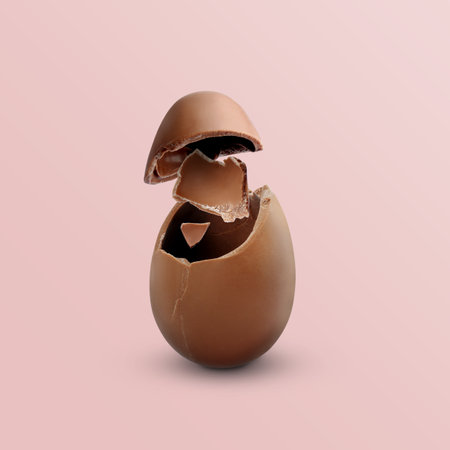 Exploded milk chocolate egg on pale light pink backgroundの写真素材