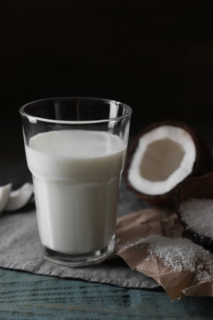 Glass of coconut milk, flakes and nut pieces on wooden tableの写真素材