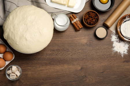 Flat lay composition with fresh yeast dough and different ingredients on wooden table, space for...