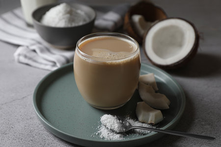 Glass of coffee with coconut milk, pieces and flakes on light gray tableの写真素材