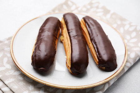 Delicious eclairs covered with chocolate on gray table, closeupの写真素材