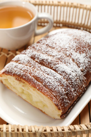 Delicious yeast dough cake and tea on wicker tray, closeupの写真素材