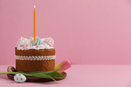 Traditional Easter cake with meringues, candle, decorated eggs and tulip on pink background. Space for textの写真素材