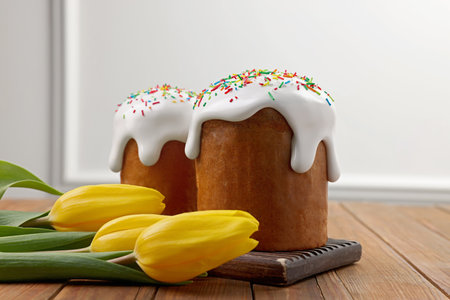 Tasty Easter cakes and flowers on wooden table