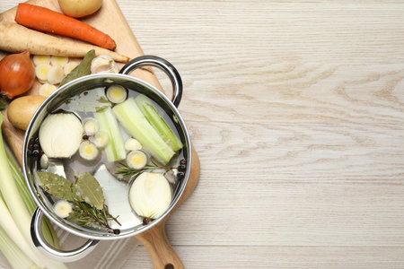 Pot and different ingredients for cooking tasty bouillon on white wooden table, flat lay. Space for textの写真素材