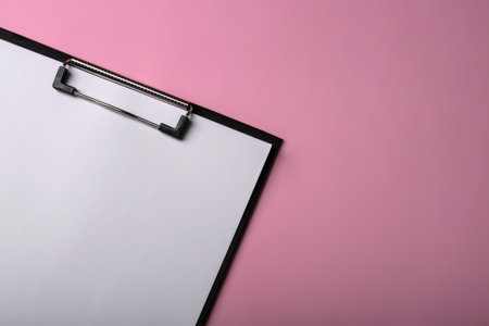 Black clipboard with sheet of blank paper on pink background, top view. Space for textの写真素材