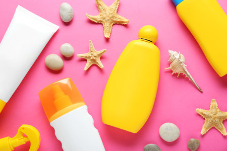 Different suntan products, starfishes and stones on pink background, flat layの写真素材