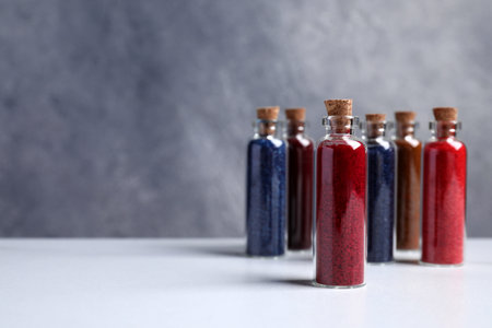 Glass bottles with different food coloring on white marble table. Space for textの写真素材
