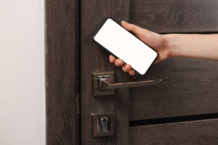 Woman unlocking door using smartphone, closeup viewの写真素材