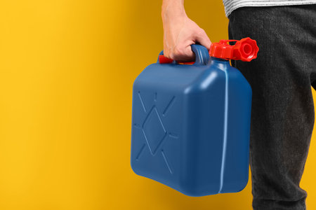 Man holding blue canister on orange background, closeup. Space for textの写真素材