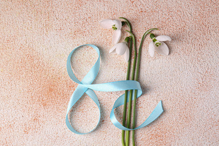 Beautiful snowdrops and number 8 made of ribbon on color textured background, flat lay