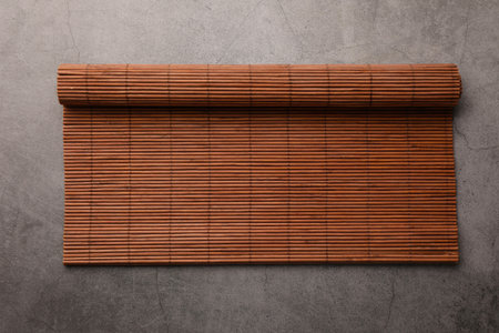 Rolled bamboo mat on gray table, top view. Space for textの写真素材