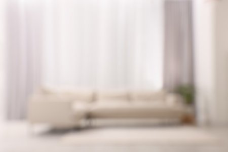 Blurred view of comfortable sofa and window with beautiful curtains in room. Interior designの写真素材