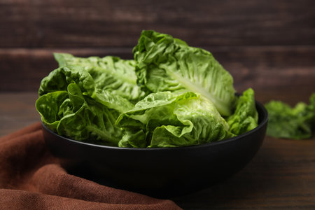 Bowl of fresh green romaine lettuces on wooden table, closeupの写真素材