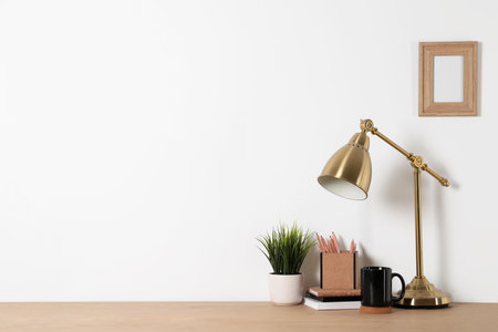 Comfortable workplace with wooden desk near white wall at homeの写真素材