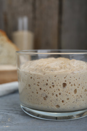 Glass jar with sourdough on gray wooden table, closeupの写真素材