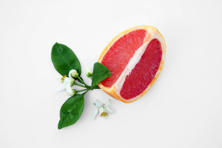 Cut fresh ripe grapefruit and green leaves on white background, top viewの写真素材