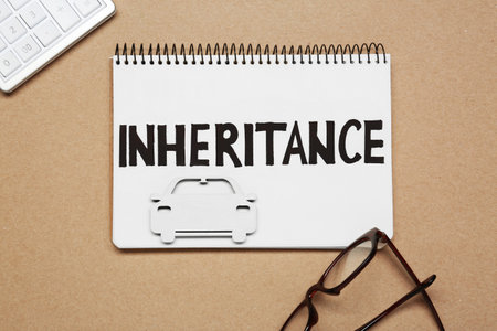 Notebook with word Inheritance, car figure and glasses on brown background, flat layの写真素材