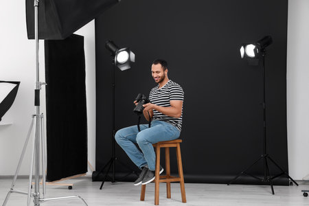 Young professional photographer with camera in modern photo studioの写真素材