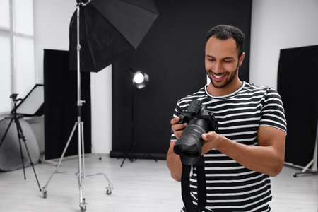 Young professional photographer with camera in modern photo studio, space for textの写真素材