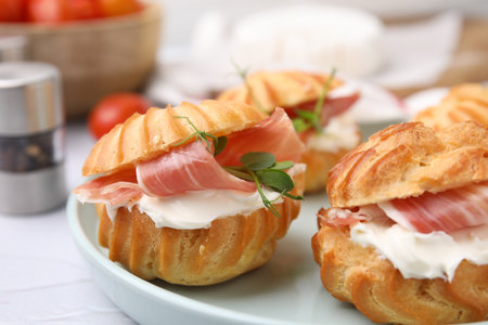 Delicious profiteroles with cream cheese and prosciutto on white table, closeupの写真素材