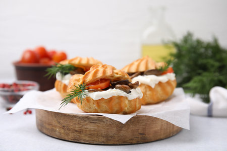 Delicious profiteroles with cream cheese, mushrooms, tomato and dill on white table, closeup