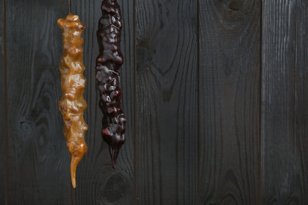 Delicious sweet churchkhelas hanging on wooden wall. Space for textの写真素材