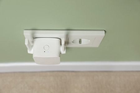 Wireless WiFi repeater on light green wall indoors, above view