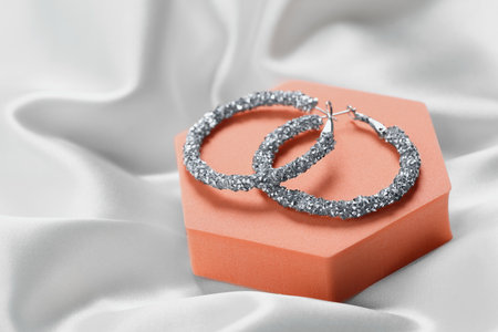 Beautiful earrings on orange podium. Luxury jewelry