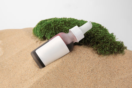 Bottle of serum and moss on sand against white background, closeup. Cosmetic productの写真素材