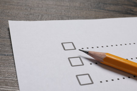 Paper sheet with checkboxes and pencil on wooden table, closeup. Checklist
