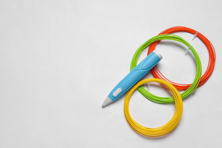 Stylish 3D pen and colorful plastic filaments on white background, flat lay, Space for textの写真素材