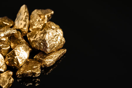 Pile of shiny gold nuggets on black background, closeup. Space for textの写真素材