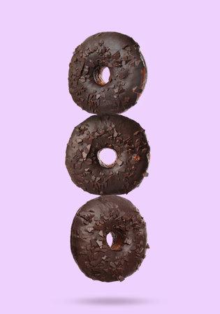Tasty chocolate donuts falling on pastel violet backgroundの写真素材