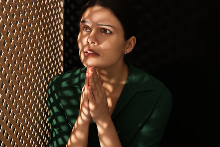 Woman praying to God during confession in boothの写真素材