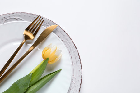 Stylish table setting with cutlery and flowers on white background, flat lay. Space for textの写真素材