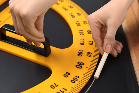 Woman drawing with chalk and protractor on blackboard, closeup