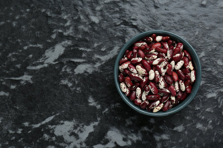 Bowl with dry kidney beans on black textured table, top view. Space for textの写真素材