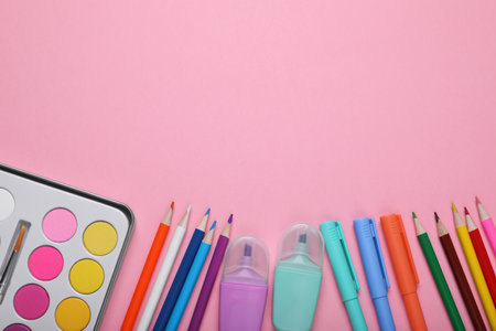 Watercolor palette, colorful markers and pencils on pink background, flat lay. Space for textの写真素材