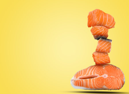 Cut fresh salmon falling on yellow background, space for textの写真素材