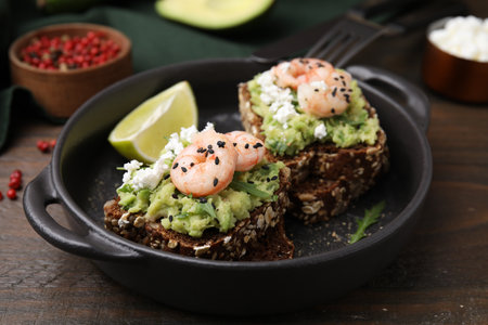 Delicious sandwiches with guacamole, shrimps and black sesame seeds on wooden tableの写真素材