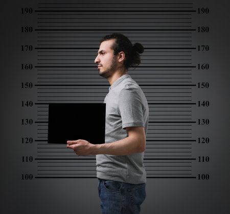 Criminal mugshot. Arrested man with blank card against height chartの写真素材