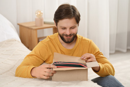 Happy man opening parcel at home. Internet shoppingの写真素材