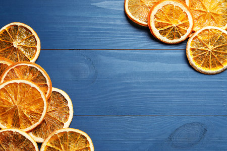 Dry orange slices on blue wooden table, flat lay. Space for textの写真素材
