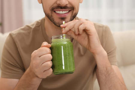 Happy man drinking delicious fresh smoothie indoors, closeupの写真素材