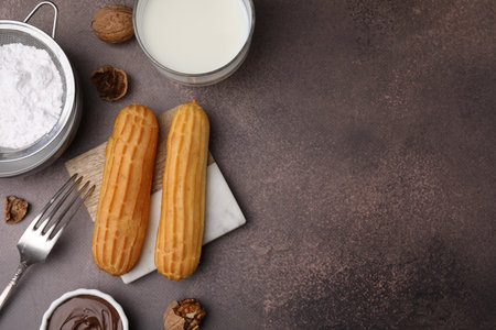 Delicious eclairs, chocolate paste, milk and walnuts on gray table, flat lay. Space for textの写真素材