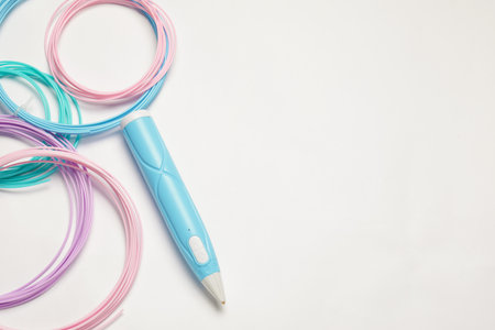 Stylish 3D pen and colorful plastic filaments on white background, flat lay. Space for text