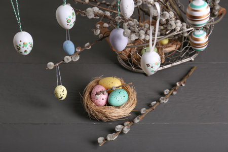 Beautiful willow branches with painted eggs and Easter decor on light gray wooden table, above view