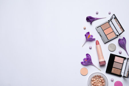Flat lay composition with different makeup products and beautiful flowers on white background. Space for textの写真素材